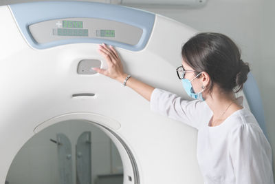 Woman x-ray doctor adjusting computer tomography scanner machine to make ct test