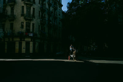 Man riding bicycle on road against buildings in city