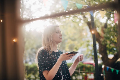 Smiling young woman using mobile phone outdoors