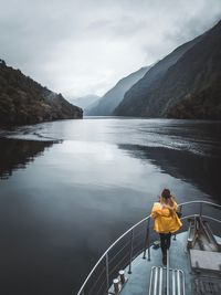 Rear view of woman looking at sea while standing on boat against sky