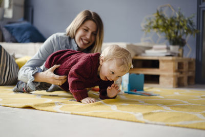 Mother and son playing at home, baby learning to crawl