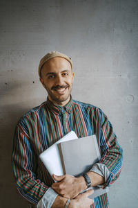 Portrait of young man standing against wall