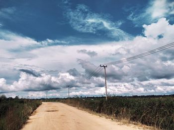 Road amidst field against sky