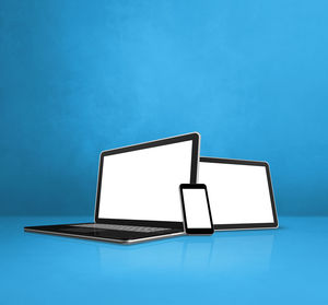 Low angle view of laptop on table against blue wall