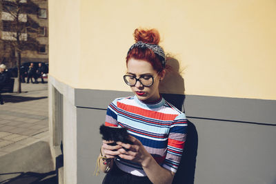 Young woman standing against wall