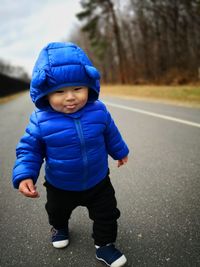 Full length of cute baby boy wearing winter jacket while walking on road