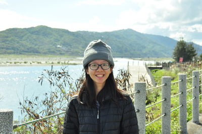 Portrait of young woman standing against lake