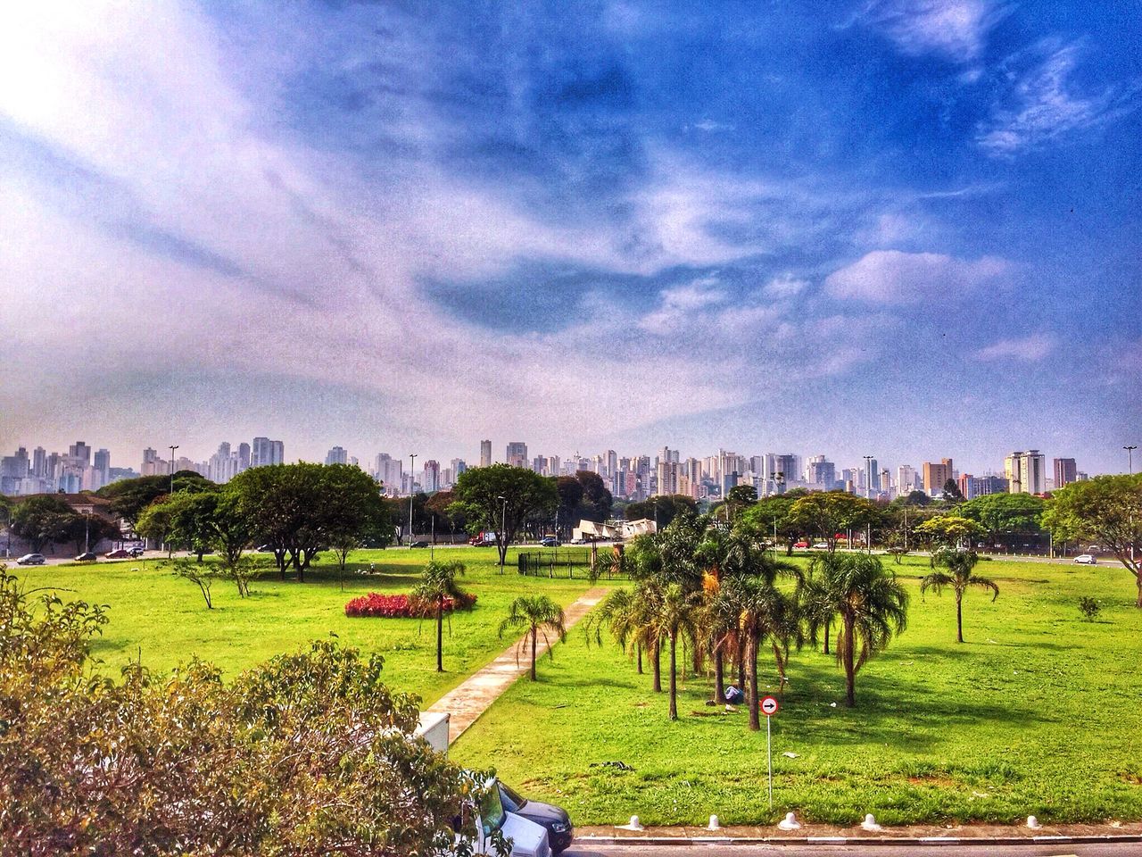 grass, building exterior, sky, architecture, built structure, cloud - sky, tree, cloudy, green color, city, cloud, lawn, field, park - man made space, grassy, growth, landscape, nature, cityscape, residential building