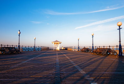 Street lights by sea against blue sky