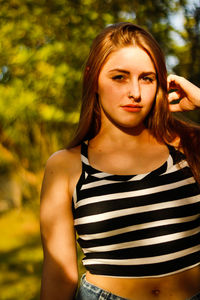 Portrait of young woman standing at park