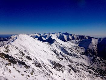 Scenic view of snow covered mountains against clear sky