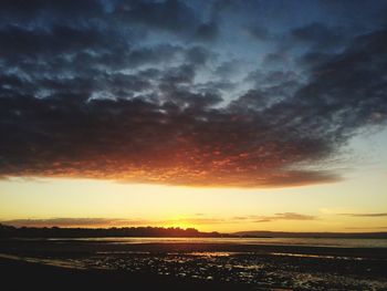 Scenic view of sea against cloudy sky at sunset