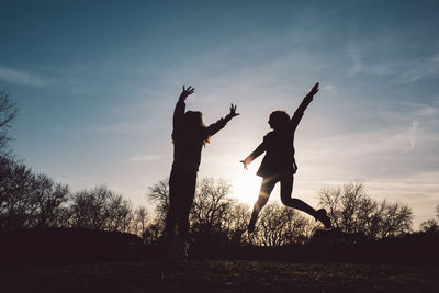 Full length of silhouette people jumping at sunset