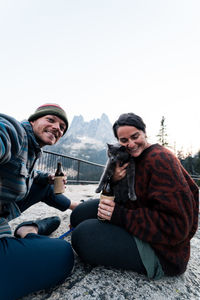 Portrait of man and woman holding loving embracing cat while sitting on rock white background