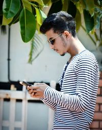 Side view of man using mobile phone while standing at park