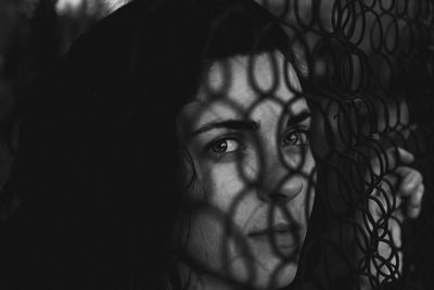 Close-up portrait of young woman by fence