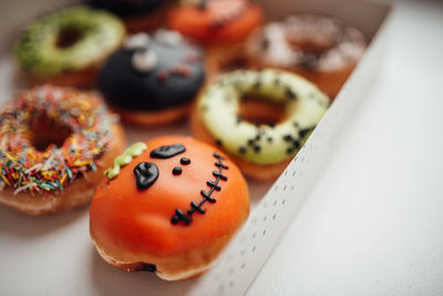 Assortment of halloween monsters with funny faces donuts in box at home interior