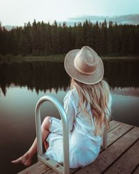 Rear view of woman sitting by lake