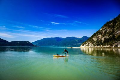 Teenage boy paddleboarding in sea against sky