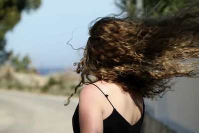 Rear view of a woman with hair tossed in wind