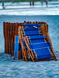 Blue chairs in swimming pool against sea