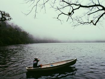 Man on boat in lake against sky