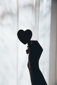 Close-up of hand holding heart shape window