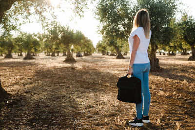 Side view of woman standing at olive orchard