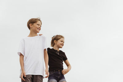 Siblings standing against white background