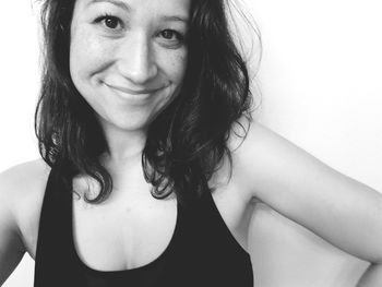 Close-up portrait of smiling young woman over white background