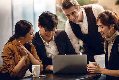 Business people brainstorming while looking at laptop in office