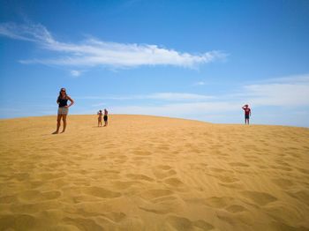 People standing at desert against sky