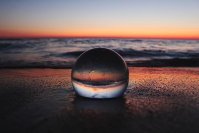 Close-up of water on beach against sky during sunset