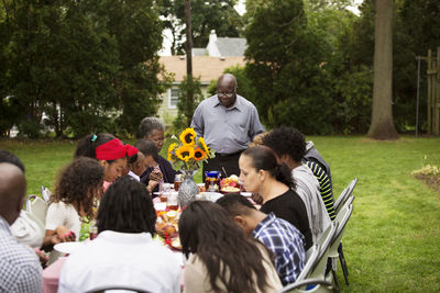 Family and friends having food at table in backyard