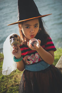 Portrait of girl wearing witch hat holding skull and crystal ball