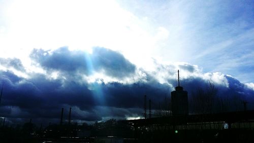 Low angle view of communications tower against cloudy sky