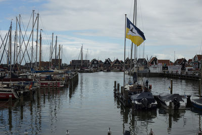 Sailboats moored in harbor against sky