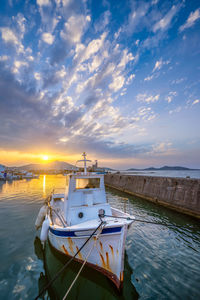 Boat moored in sea against sky during sunset