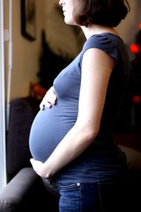 Midsection side view of pregnant woman standing at home