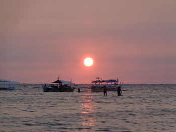 Silhouette boat in sea against sky during sunset