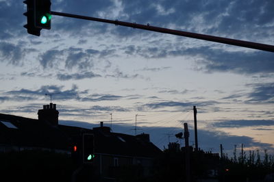 Silhouette of street light against cloudy sky