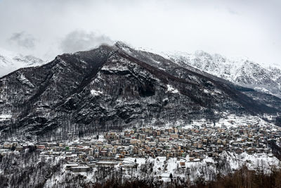 Aerial view of houses on snow covered landscape against sky