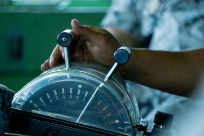 Close-up of hand holding clock against blurred background