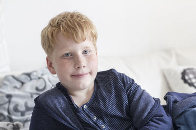 Portrait of smiling boy lying on bed at home