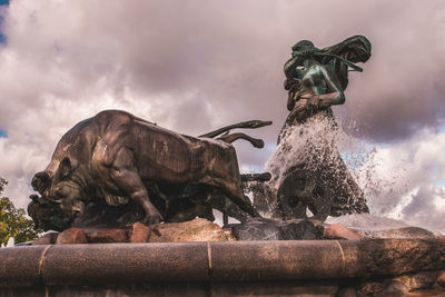 Statue by water against sky