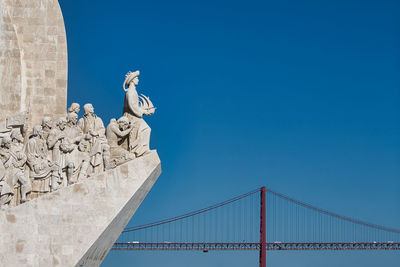 Low angle view of statue of bridge against blue sky