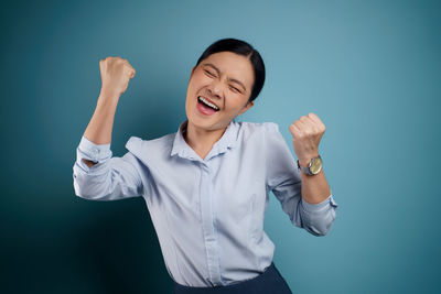 Smiling young woman standing against blue background