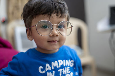 Close-up portrait of cute boy wearing eyeglasses at home