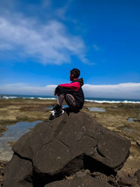 Full length of man on rock at beach against sky
