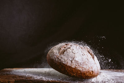 Spectacular image of fresh and rustic golden bread falling wood kitchen table with flour explosion